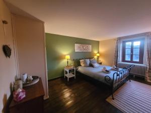 a bedroom with a bed and a green wall at Chambre d'hôtes Le Puy Maury in Augne
