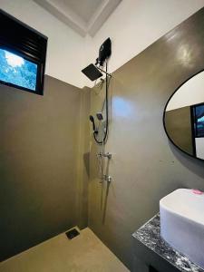 a bathroom with a shower with a sink and a mirror at Ancy Villa in Dickwella