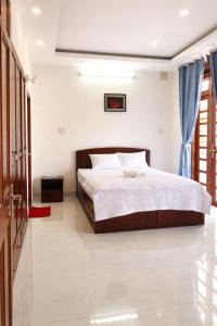a bedroom with a large bed with blue curtains at Green Ville Hotel Đồng Nai in Xa Dau Giay