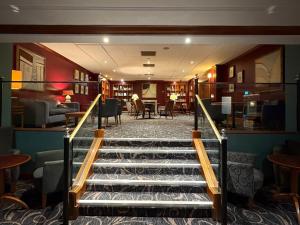 a staircase leading to a library with chairs and tables at Apollo Hotel in Basingstoke