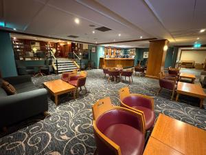 a waiting room with tables and chairs and a library at Apollo Hotel in Basingstoke