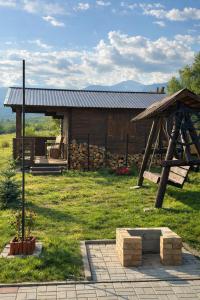 a log cabin with a porch and a swing at Cabanuta Din Deal in Racoviţa