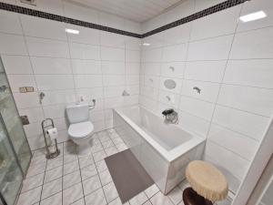 a white bathroom with a tub and a toilet at Ferienwohnung Roersch in Freudenburg