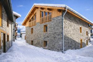 a stone building with a balcony in the snow at Les Framboisiers by Lodji in Saint-Marcel