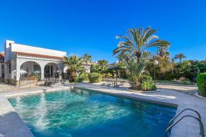 a swimming pool in front of a house with palm trees at Villa La Font with pool and bbq in Alicante