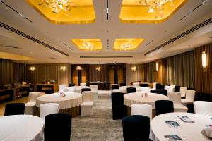 a dining room with white tables and chairs and chandeliers at Gemini Continental, Hazratganj in Lucknow