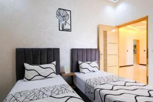a bedroom with two beds and a clock on the wall at Riad Bollywood-Star Stay A in Benguerir