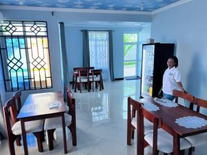 a man standing in a room with tables and chairs at ANITHA EXECUTIVe LODGE in Kibaha