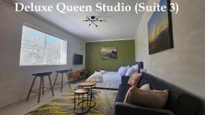 a bedroom with a bed and a couch and stool at Deep South Suites in Cape Town