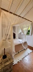 a bedroom with a canopy bed with curtains and a rug at Vila Pitanga Trancoso in Trancoso