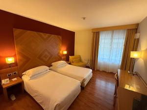 a hotel room with two beds and a window at Hotel Pergola in Legnago