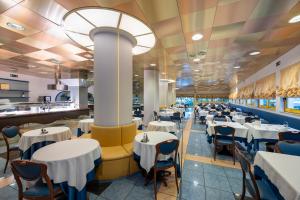 a dining room with white tables and chairs at Hotel Luna in Bibione