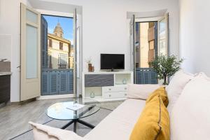 a living room with a white couch and a tv at Apartamentos Calle Larios in Málaga
