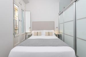 a white bedroom with a large bed and two windows at Apartamentos Calle Larios in Málaga