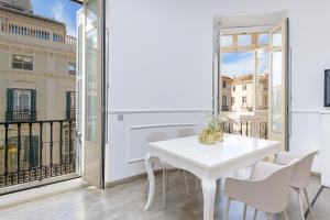 a white dining room with a white table and chairs at Apartamentos Calle Larios in Málaga