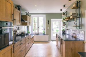 a large kitchen with wooden cabinets and black counter tops at Maison d'hôtes le Prieuré du Preux in Sepeaux saint romain