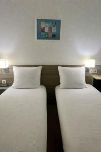two beds in a hotel room with white pillows at Contact Hôtel Marseille Aubagne in La Penne-sur-Huveaune