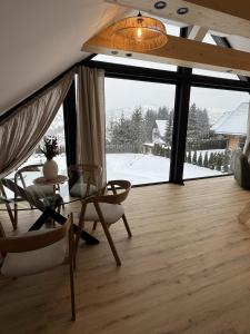a living room with a table and chairs and a large window at Apartament Świerkowa Osada in Istebna