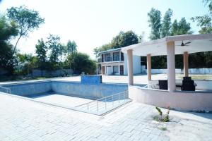 a swimming pool with a gazebo next to a house at Badrika Farm's in Rewa
