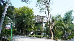 a house in the middle of a road with trees at Badrika Farm's in Rewa