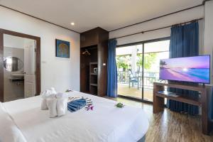 a bedroom with a large white bed with a flat screen tv at Three Trees Samui Resort - Sarocha Villa in Lamai