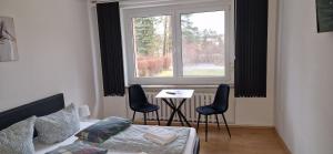 a bedroom with a bed and a table and a window at Pension Stechlinsee in Neuglobsow