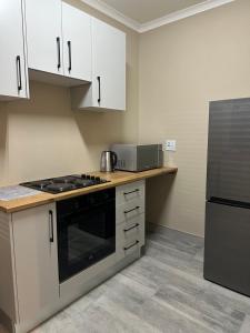 a kitchen with white cabinets and a black appliance at Guesthouse Le Michele in Swakopmund +5 photos