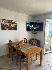 a dining room table with chairs and a tv on the wall at Andreja in Kustići +15 photos
