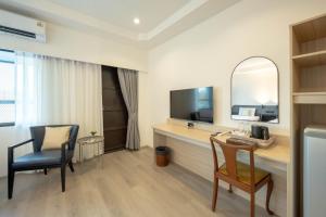a room with a desk with a television and a chair at The Krungkasem Srikrung Hotel in Bangkok