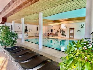 a large swimming pool with chairs in a building at Berghoteltirol in Jungholz