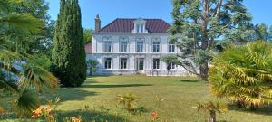 a large white house with trees in the yard at La Carte Postale in Oye-Plage