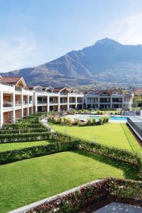 a view of a resort with a garden and mountains at Lago Dorato Luxury Apartments - Lake Como View in Colico