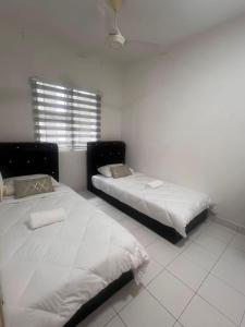 two beds in a white room with a window at AmyHana Cozynest in Putrajaya