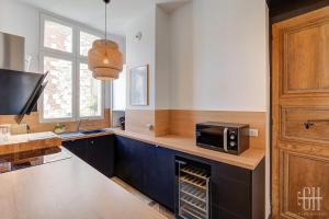 a kitchen with a microwave on top of a counter at Spacieux Appartement - Type Haussmannien - Wifi in Tours