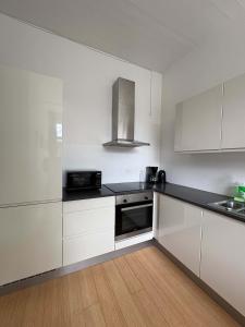 a kitchen with white cabinets and a black counter top at PENDING Queen Bedroom with Balcony in Shared Apartment in Copenhagen