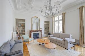 a living room with a couch and a table and a chandelier at Spacieux Appartement - Type Haussmannien - Wifi in Tours