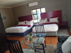 a hotel room with two beds and a glass table at Emangweni Guest House in Vryheid +22 photos