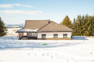 a white house in the snow with trees at Planinska kuća Ema in Kupres