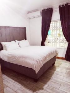 a bedroom with a large bed and a window at Peace Cottages Uvongo. in Uvongo Beach +243 photos