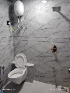 a bathroom with a toilet and a marble wall at Hotel Pine Lake in Ahmedabad