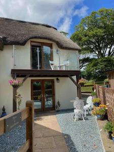a thatched cottage with a patio and a table and chairs at 1 Bed in West Putford oc-thymw in Bulkworthy