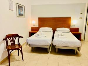a hotel room with two beds and a chair at Smart Rooms in Molinella +6 photos
