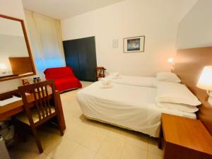 a bedroom with a bed and a desk and a red chair at Smart Rooms in Molinella