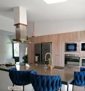 a kitchen with a large island with blue chairs at VILLA La DOLCE VITA in Sainte-Marie