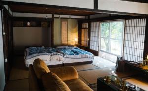 a bedroom with a bed and a couch and a window at 里の宿 門後藤 in Taketa