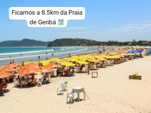 a beach with umbrellas and chairs and the ocean at Doce lar in Búzios