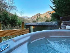 a hot tub in a yard with mountains in the background at Bluebell Lodge, Shepherd Hut with hot tub in Lake District in Coniston +16 photos