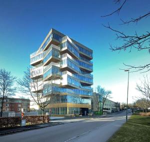 a tall glass building on the side of a street at Place Lund Apartments in Lund