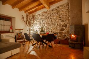 a living room with a table and chairs and a stone wall at Casa Al Castagneto in Ceniga