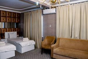 a bedroom with two beds and a chair and a couch at ORZU HOTEL in Namangan
